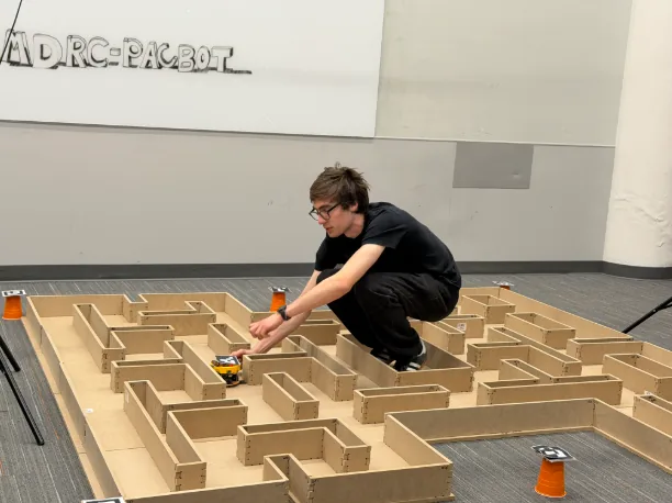 A PacBot team member placing the robot inside the competition maze at RIT